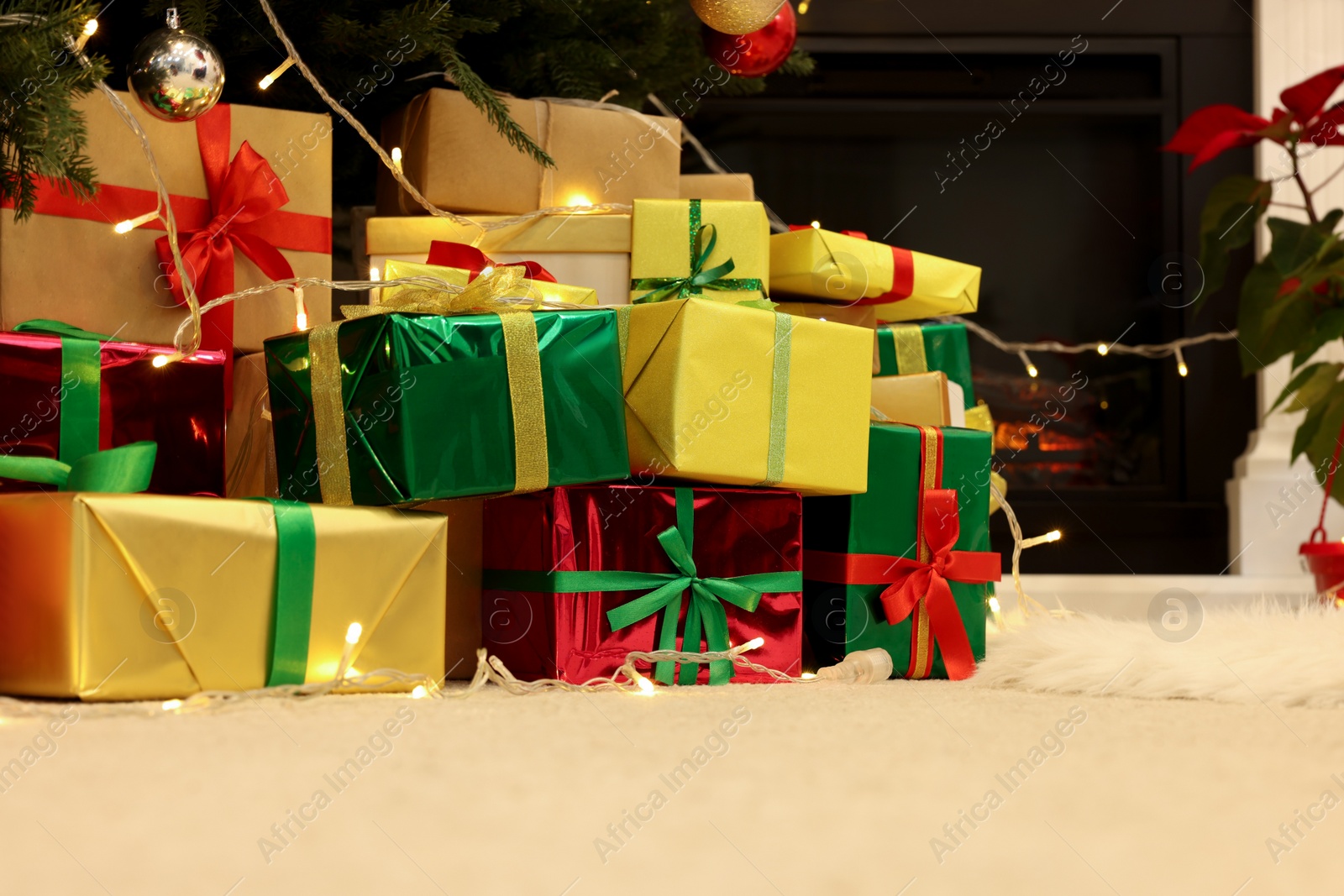 Photo of Many different gift boxes on floor near Christmas tree in room