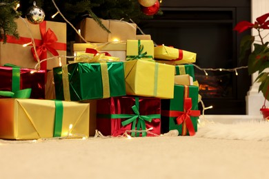 Many different gift boxes on floor near Christmas tree in room