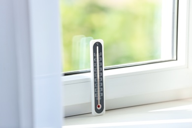 Grey weather thermometer on window sill indoors