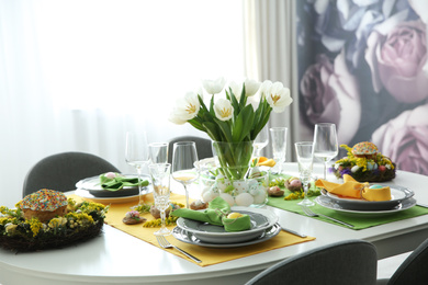 Photo of Festive Easter table setting with beautiful white tulips and eggs indoors