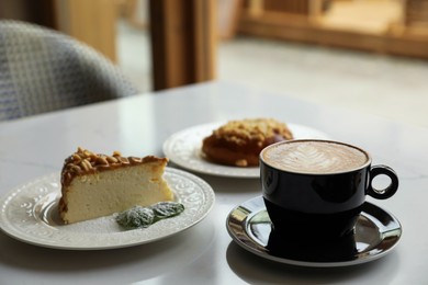 Photo of Cup of fresh coffee and desserts on table indoors