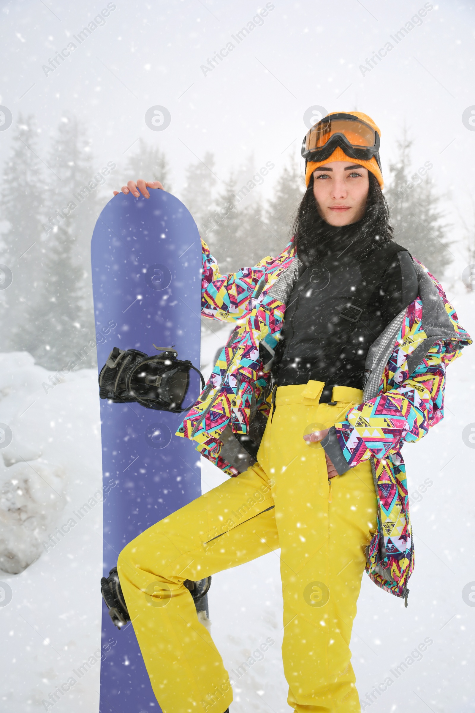 Photo of Young woman with snowboard wearing winter sport clothes outdoors