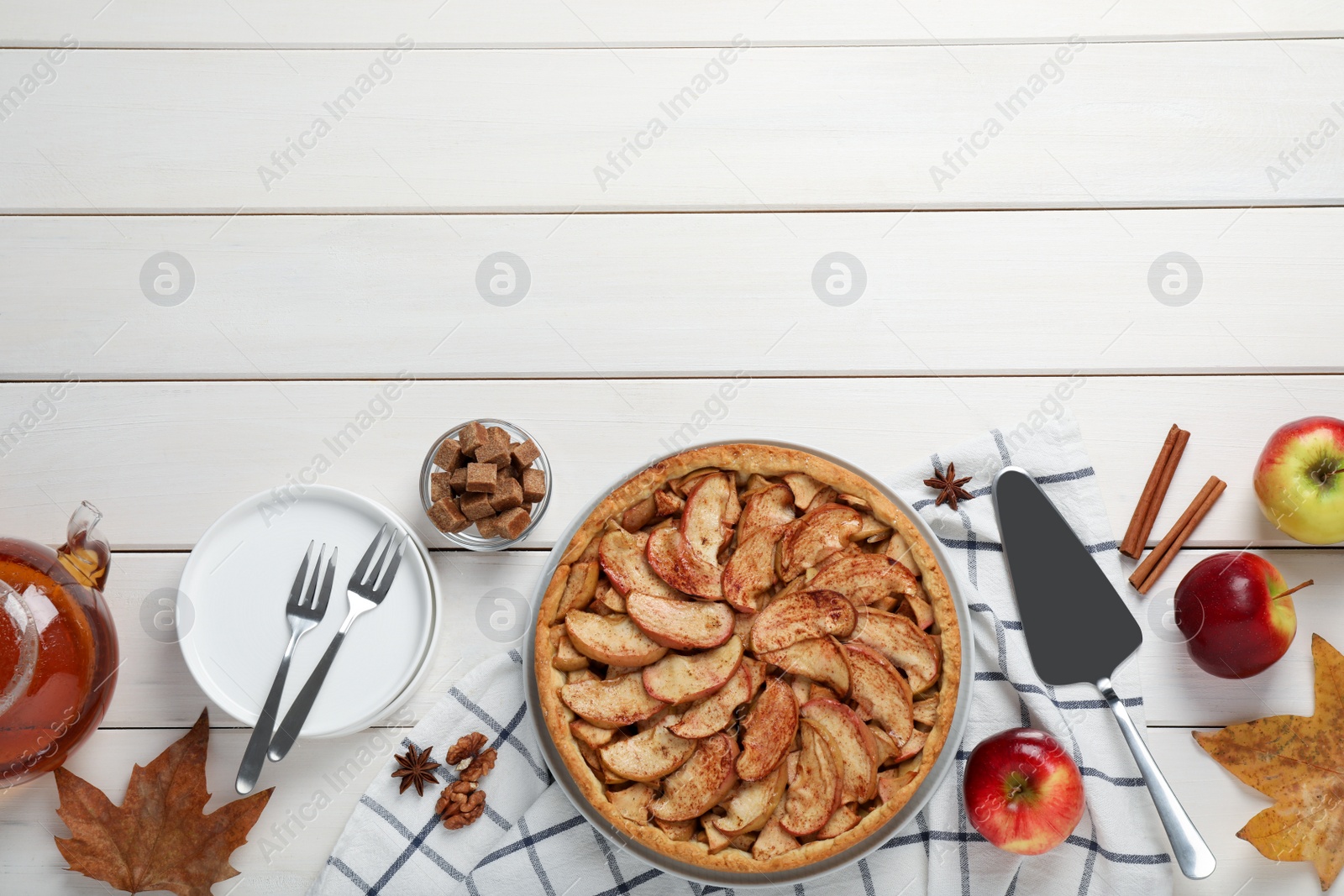 Photo of Delicious apple pie and ingredients on white wooden table, flat lay. Space for text