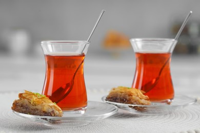 Glasses of traditional Turkish tea and delicious baklava on white table