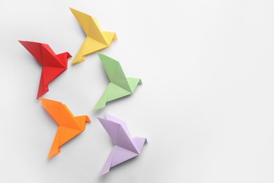 Photo of Origami art. Colorful handmade paper birds on white background, flat lay. Space for text