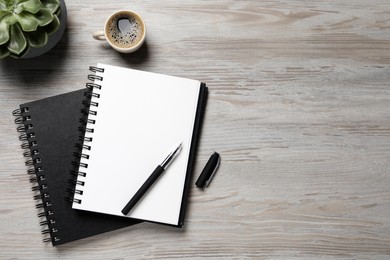 Photo of Notebooks, pen and coffee on light wooden table, flat lay. Space for text