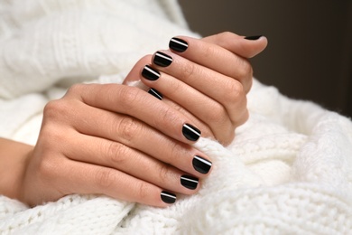 Photo of Woman with black manicure holding knitted fabric, closeup. Nail polish trends