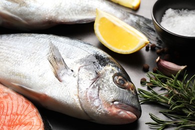 Photo of Fresh raw dorado fish, rosemary and lemon on grey table, closeup