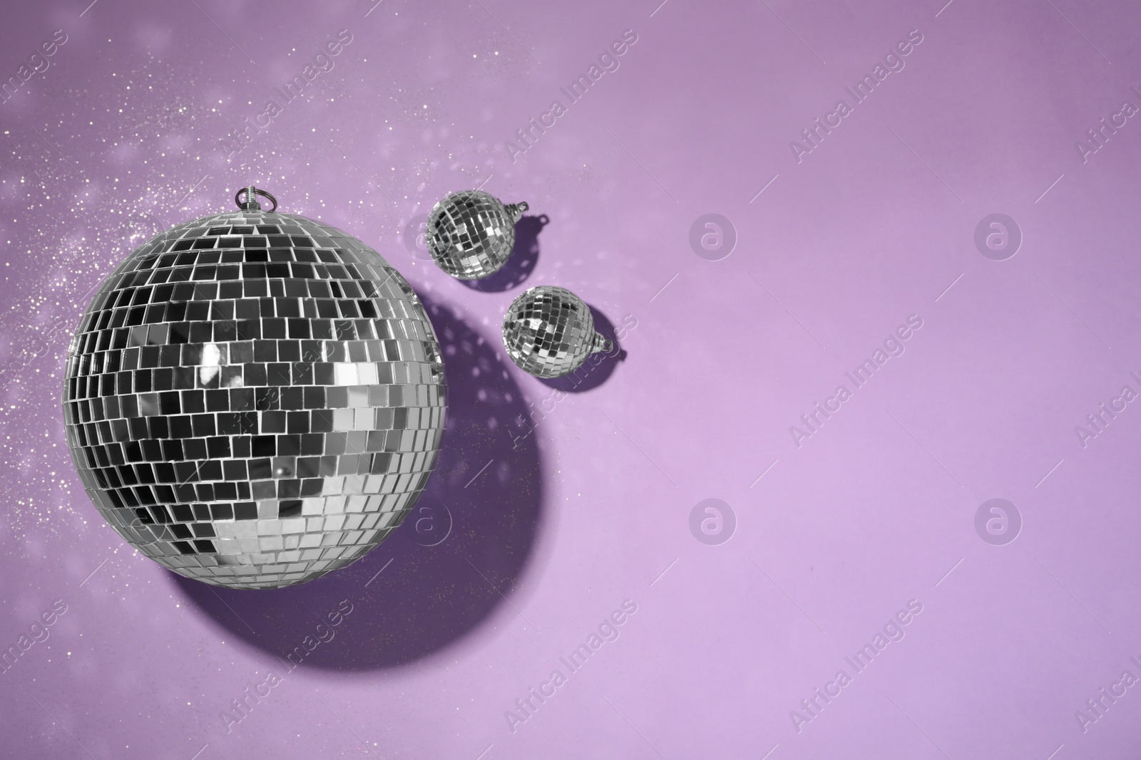 Photo of Bright shiny disco balls on violet background, flat lay. Space for text