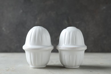 Photo of Salt and pepper shakers on light table against grey background