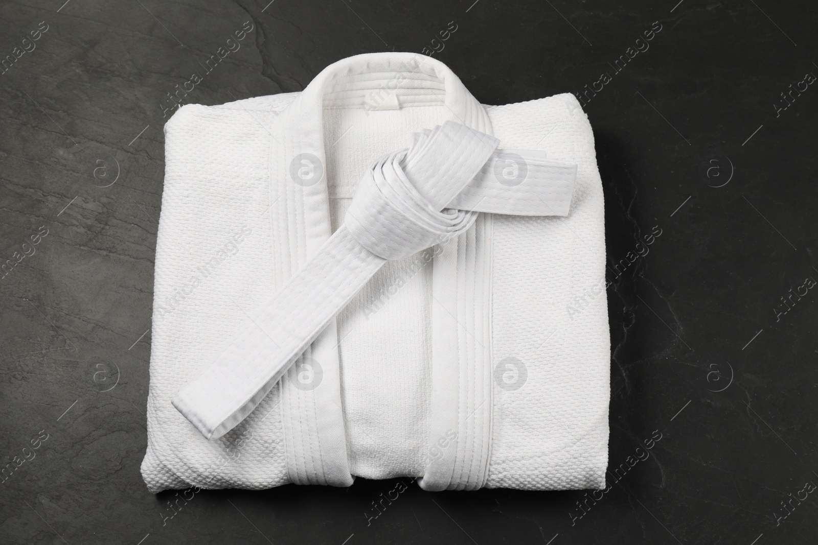 Photo of White karate belt and kimono on gray background, top view