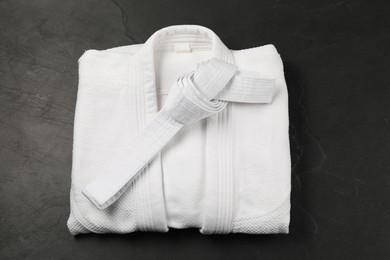 Photo of White karate belt and kimono on gray background, top view