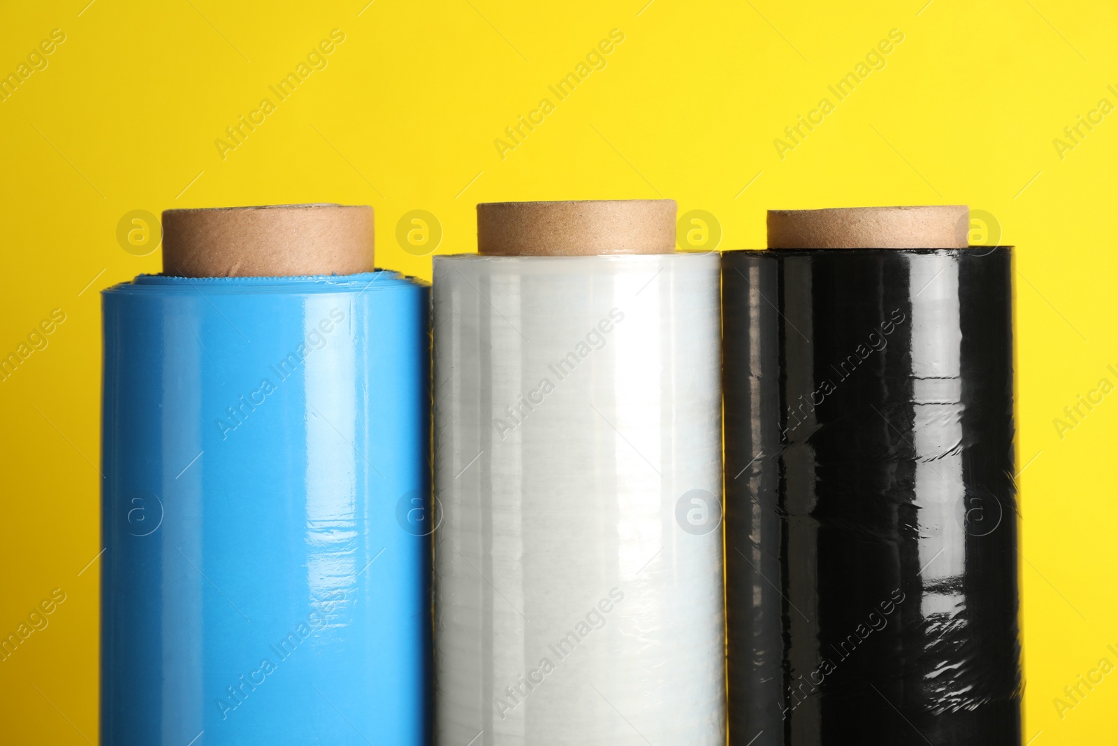 Photo of Rolls of different stretch wrap on yellow background, closeup