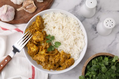 Photo of Delicious chicken curry with rice and ingredients on white marble table, flat lay