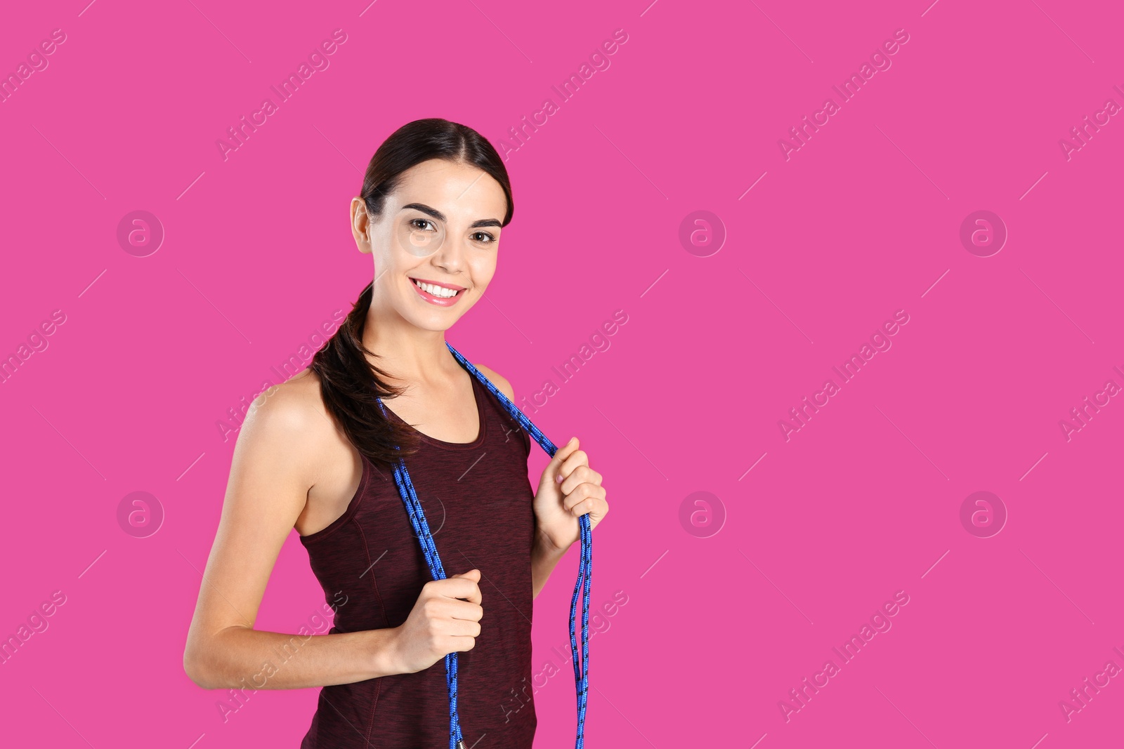 Photo of Portrait of young sportive woman with jump rope on color background. Space for text