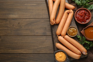 Photo of Delicious sausages, mustard, ketchup and parsley on wooden table, flat lay. Space for text