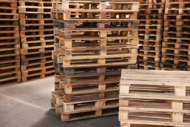 Many empty wooden pallets stacked in warehouse