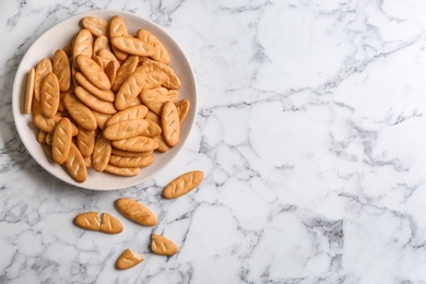 Photo of Delicious crispy crackers on white marble table, flat lay. Space for text