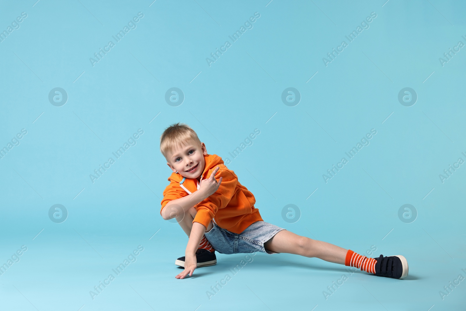 Photo of Happy little boy dancing on light blue background. Space for text