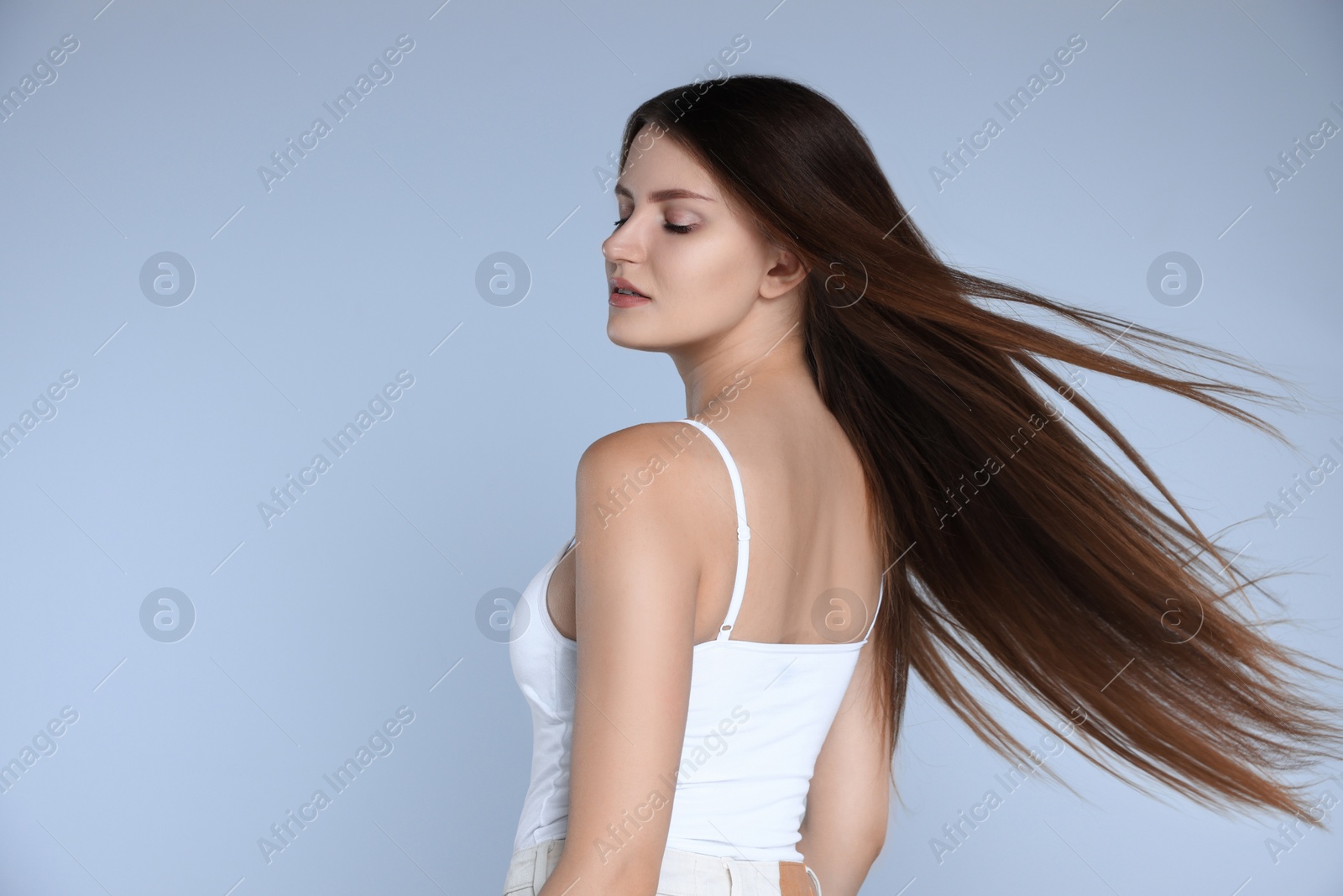 Photo of Young woman with strong healthy hair on light blue background, space for text