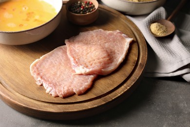 Photo of Cooking schnitzel. Raw pork slices and other ingredients on grey table