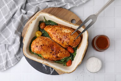 Photo of Baked chicken fillets with vegetables and marinade on white tiled table, flat lay