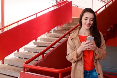 Photo of Young woman using mobile phone outdoors