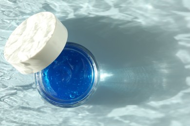 Photo of Open jar of cosmetic product on light blue background, top view. Space for text