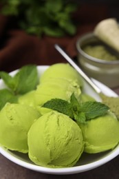 Photo of Tasty matcha ice cream and spoon with powder in bowl on table, closeup