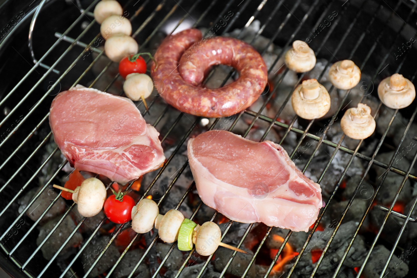 Photo of Barbecue grill with raw meat and vegetables, closeup