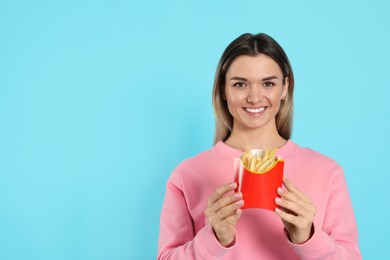 Photo of Young woman with French fries on light blue background, space for text