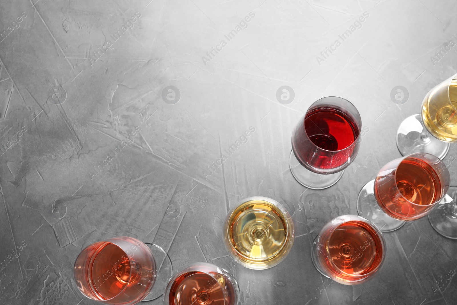 Photo of Different glasses with wine on grey background, flat lay. space for text