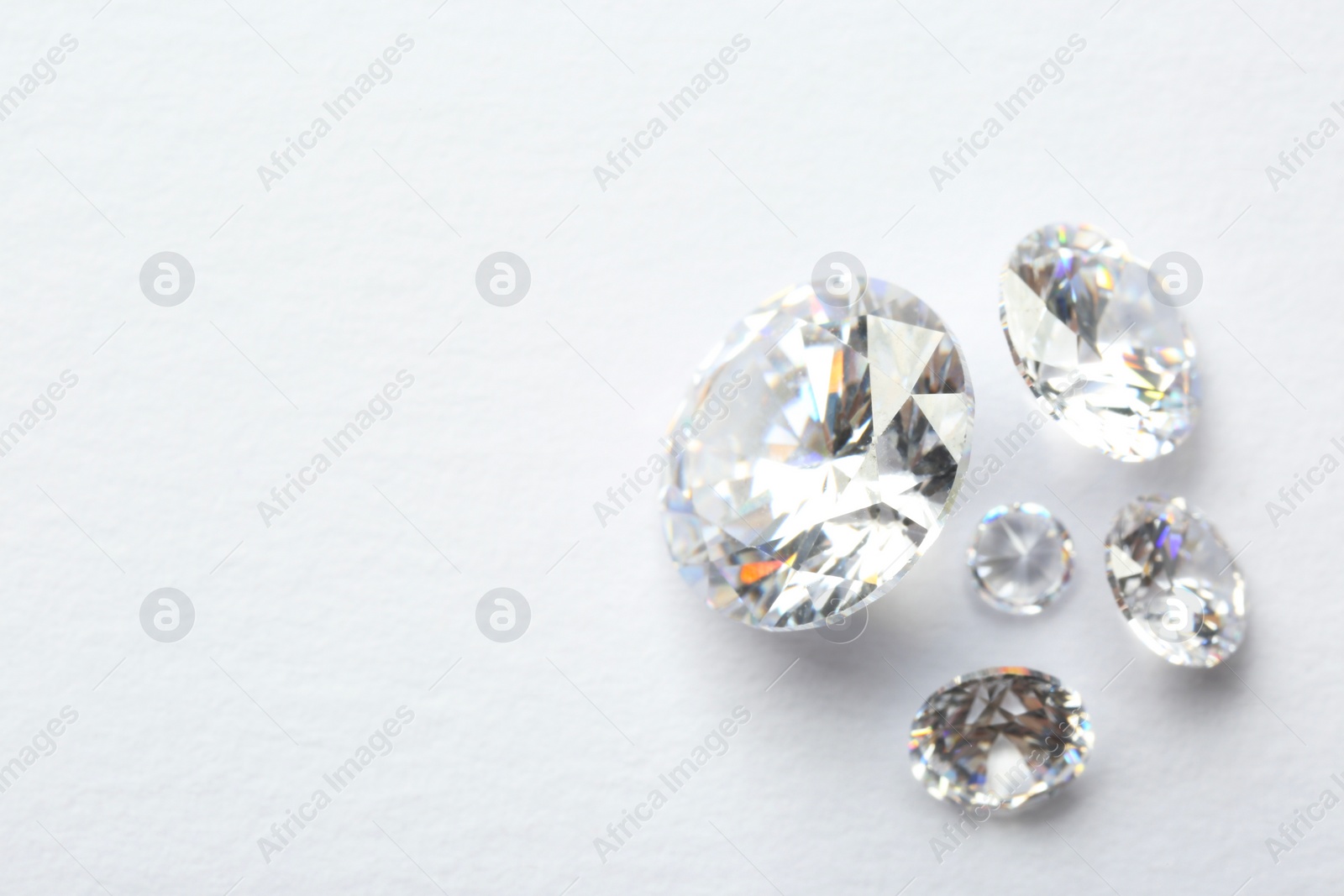 Photo of Many beautiful shiny diamonds on white background, flat lay. Space for text