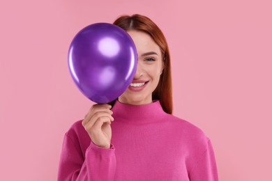 Photo of Happy woman with purple balloon on pink background
