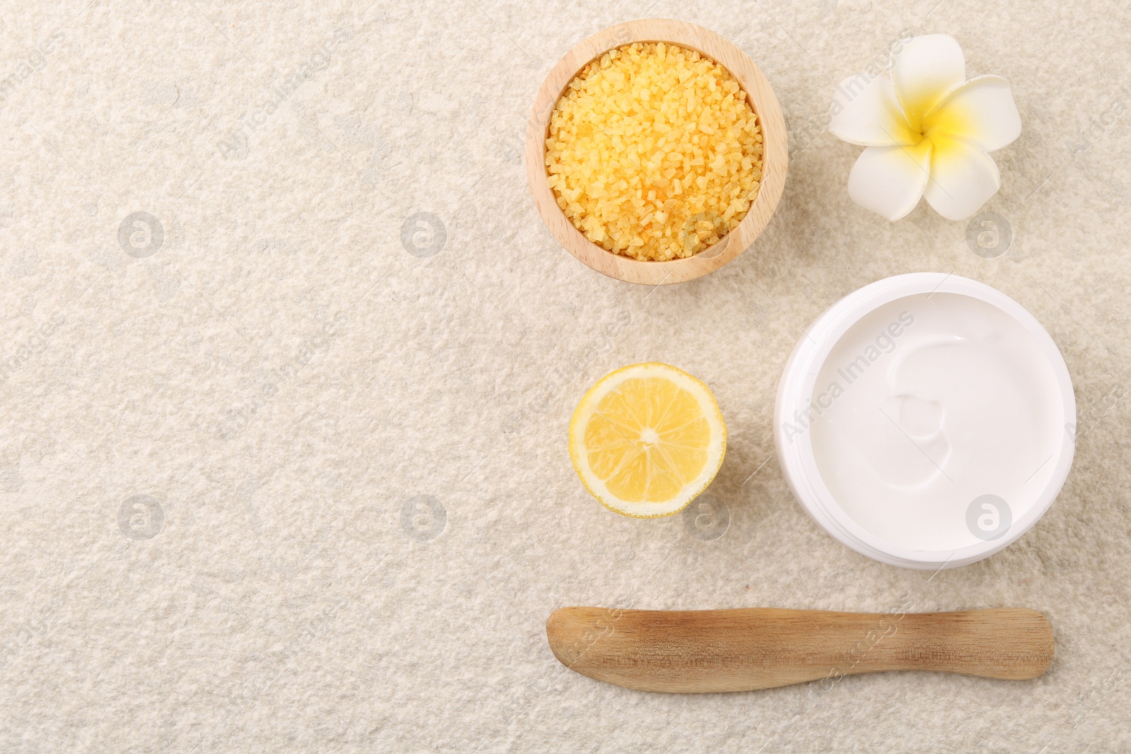 Photo of Flat lay composition with moisturizing cream in open jar and other body care products on light textured table. Space for text