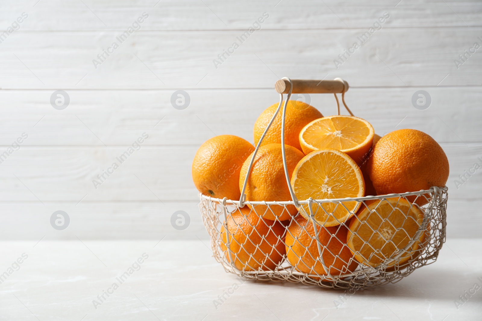 Photo of Basket with ripe oranges on table against light background. Space for text