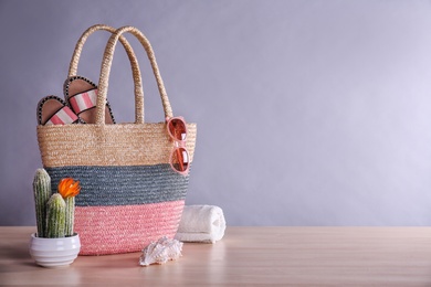 Beach objects on wooden table against color background