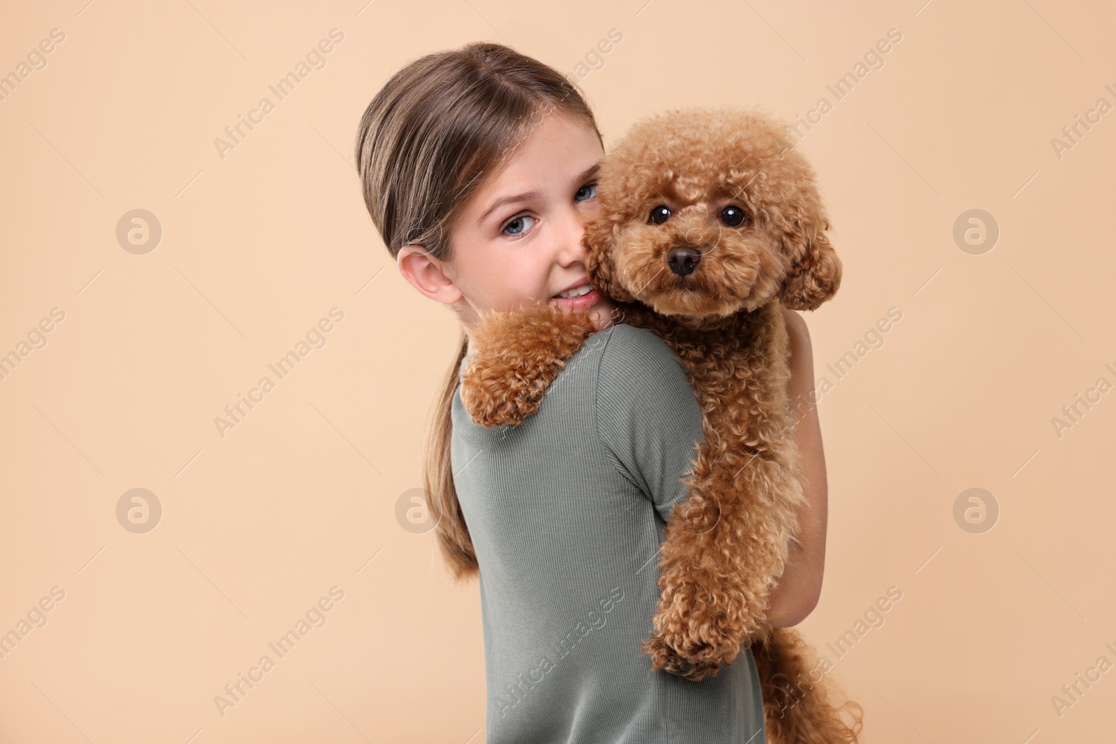 Photo of Little child with cute puppy on beige background. Lovely pet