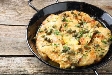 Photo of Delicious chicken piccata with herbs on wooden table. Space for text