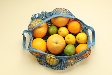 Photo of String bag with different fruits on beige background, top view