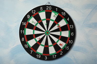 Photo of Arrows hitting dart board on light blue wall