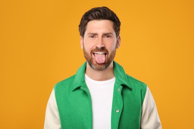 Man showing his tongue on orange background