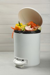 Photo of Trash bin with organic waste for composting on light background
