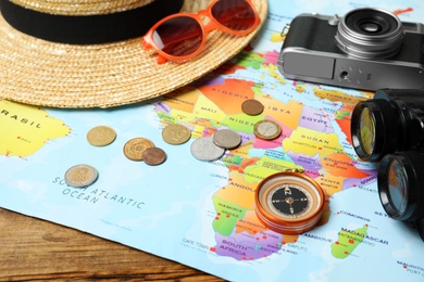 Photo of World map and different travel accessories on wooden table, closeup. Planning summer vacation trip