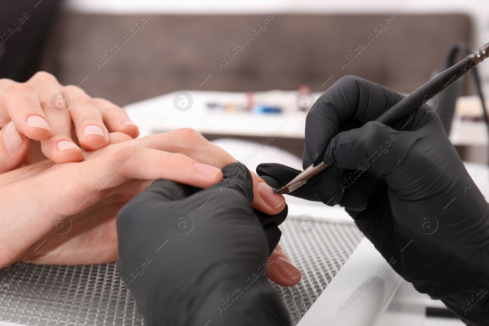 Photo of Professional manicurist working with client in salon, closeup