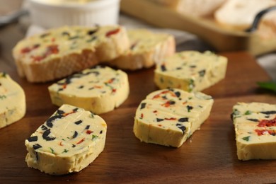 Photo of Tasty butter with olives, chili pepper, parsley and bread on table, closeup