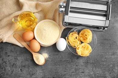 Photo of Pasta machine and products on grey background, top view