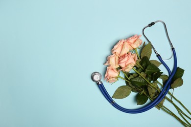 Photo of Stethoscope and flowers on light blue background, flat lay with space for text. Happy Doctor's Day