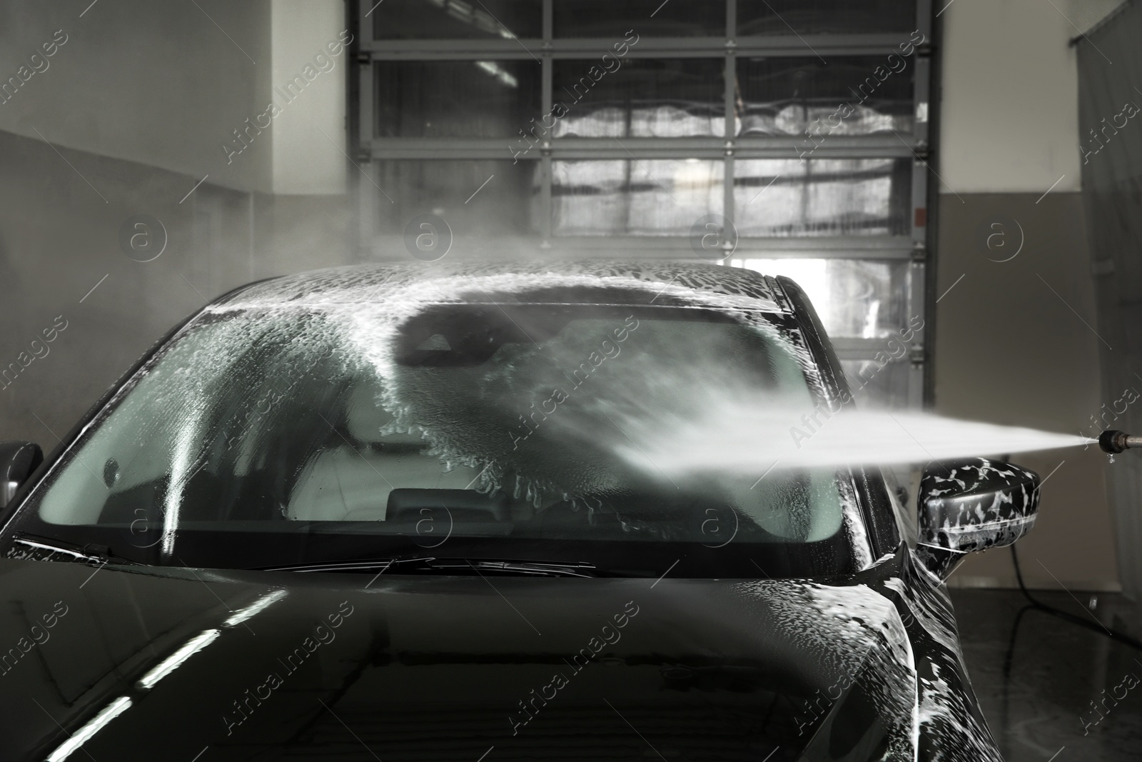 Photo of Cleaning automobile with high pressure water jet at car wash