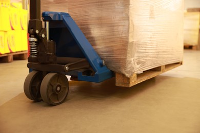 Image of Manual forklift with wrapped pallets in warehouse, closeup. Logistics concept